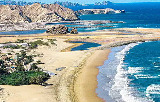 Exploring the Beaches of Oman: Which One Will You Enjoy the Most? 4 A view of Yiti Beach in Oman with golden sands, sea waves, and surrounding rocks, where pristine nature and tranquility are intertwined.