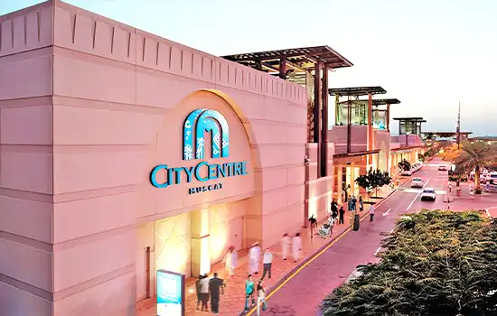An image showing the exterior view of City Centre Muscat in the Al Mawaleh area. The shopping mall features modern architecture and vibrant lighting, making it a prime destination in Muscat.