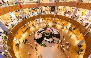 An image of a large multi-story shopping mall in Oman with a modern design and diverse visitors.