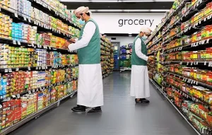Image of grocery store staff organizing shelves, related to inflation increase in Oman