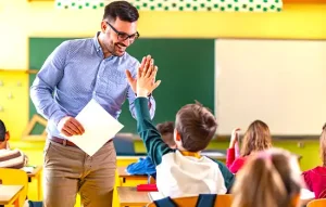 یک معلم در کلاس درسی در حال دست دادن با دانش‌آموز، نماد یک محیط آموزشی حمایت‌کننده در عمان.