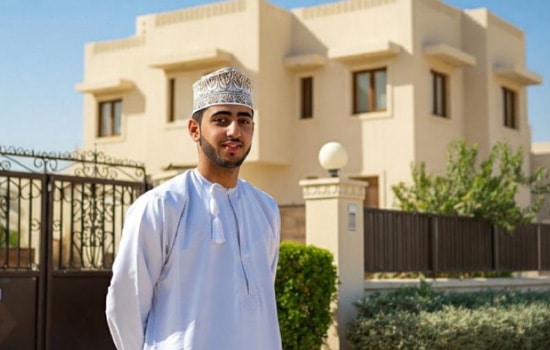 جوان عمانی با لباس سنتی در مقابل خانه ویلایی شخصی در یک منطقه مسکونی مدرن